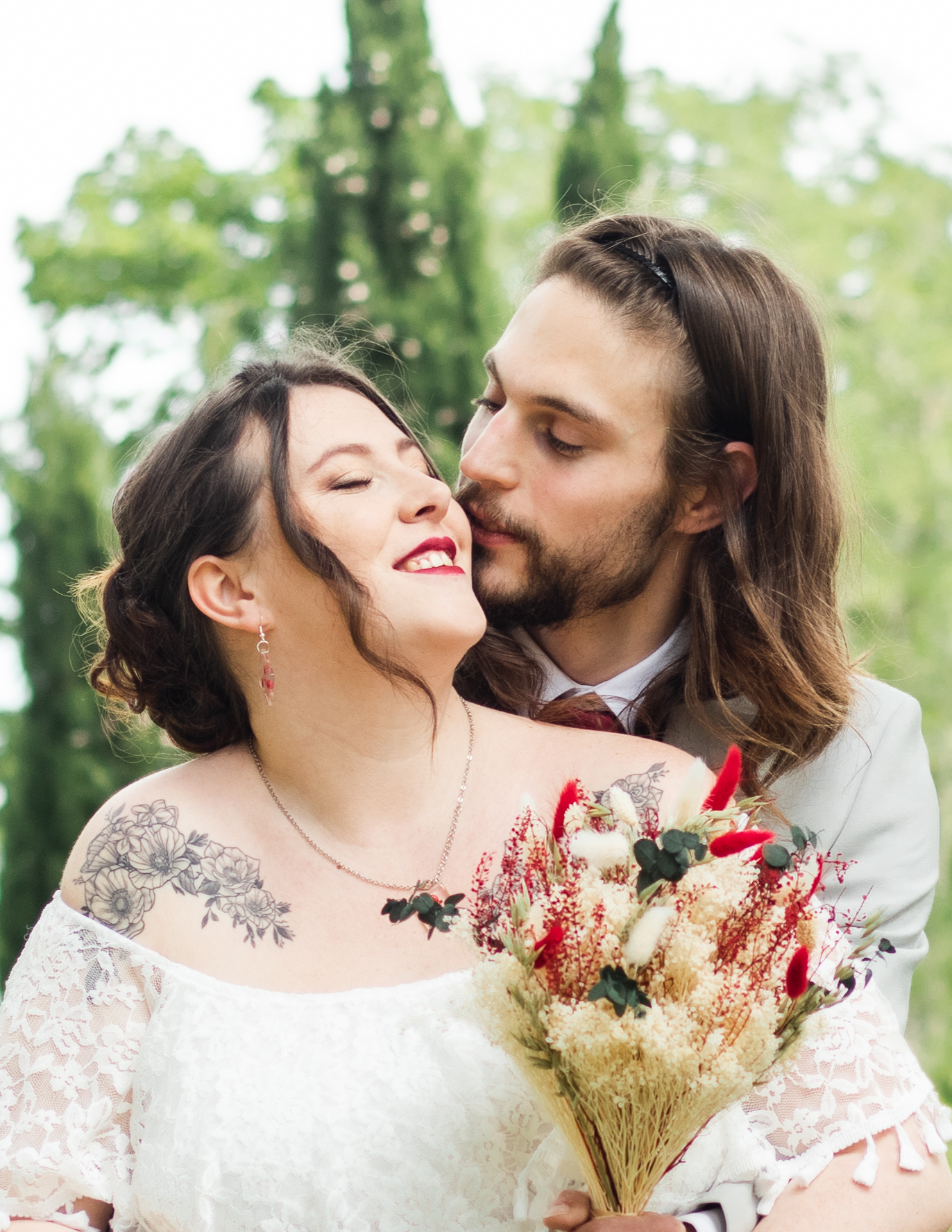 Photo de mariage à toulouse, femme brune en robe de mariée avec un bouquet de fleurs à la main et son époux derière elle